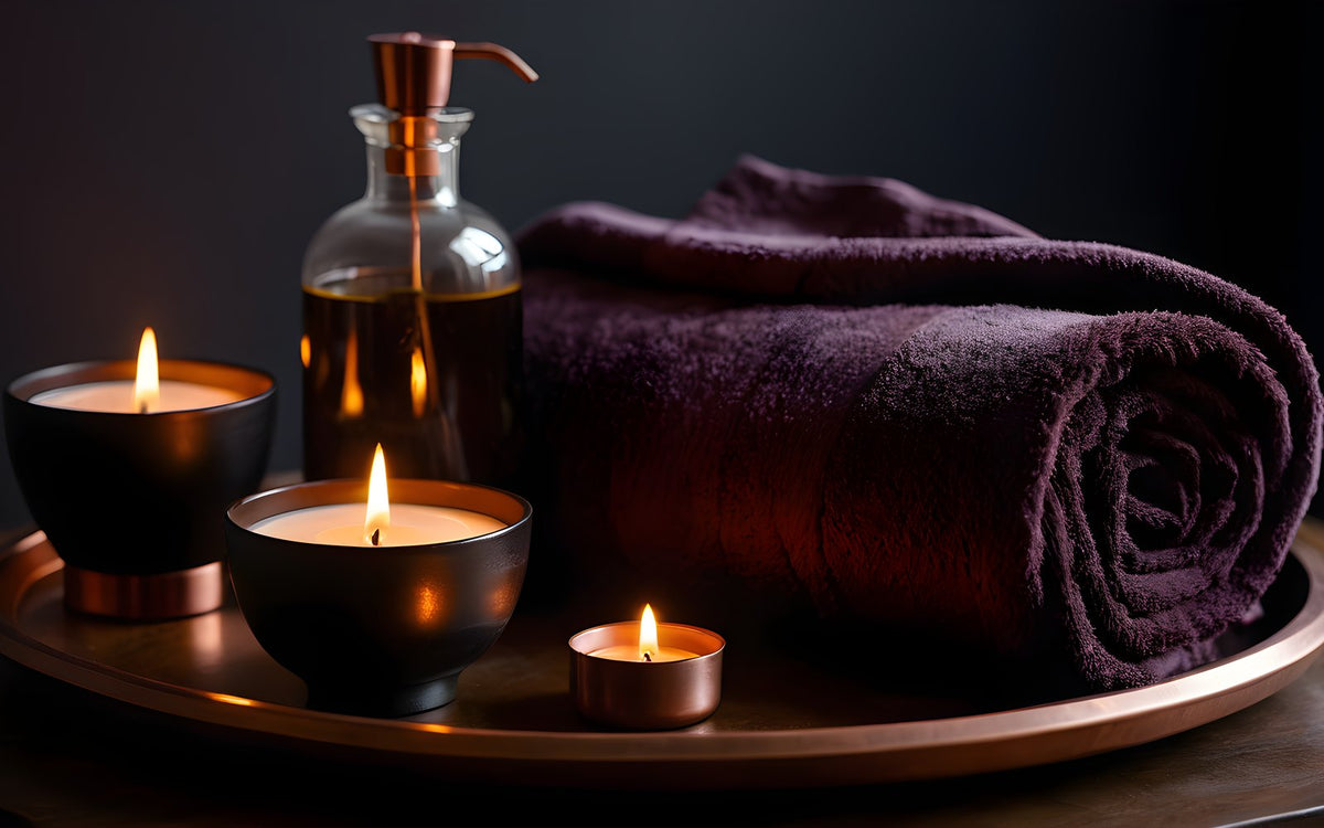 Massage oil and a rolled towel on plum satin